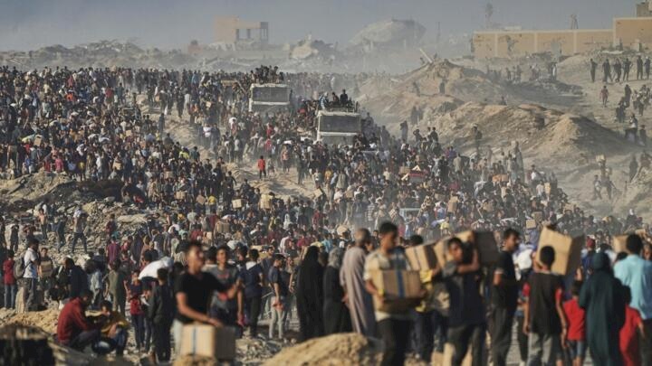 Palestinians carry sacks and boxes of food and humanitarian aid that was unloaded from a World Food Program convoy that had been heading to Gaza City in the northern Gaza Strip, Monday, June 16, 2025. © Jehad Alshrafi, AP